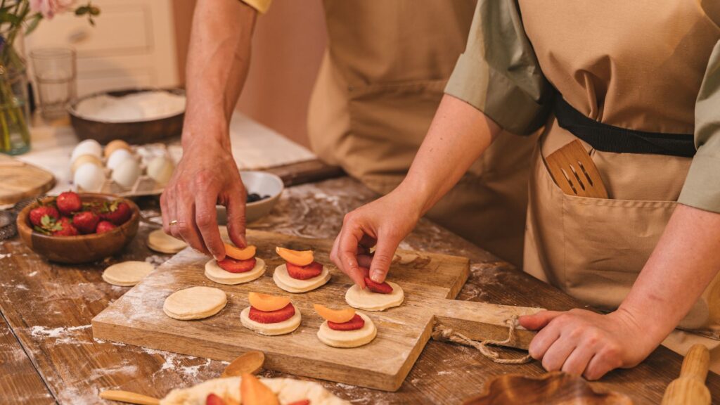 Hands making cakes with fruit